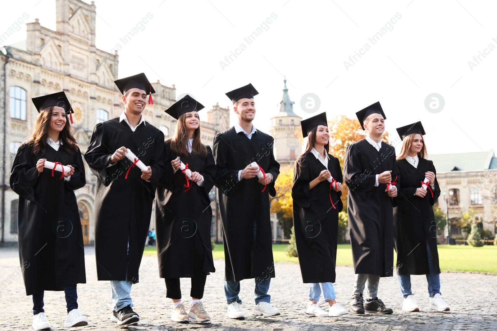 Photo of Happy students with diplomas outdoors. Graduation ceremony