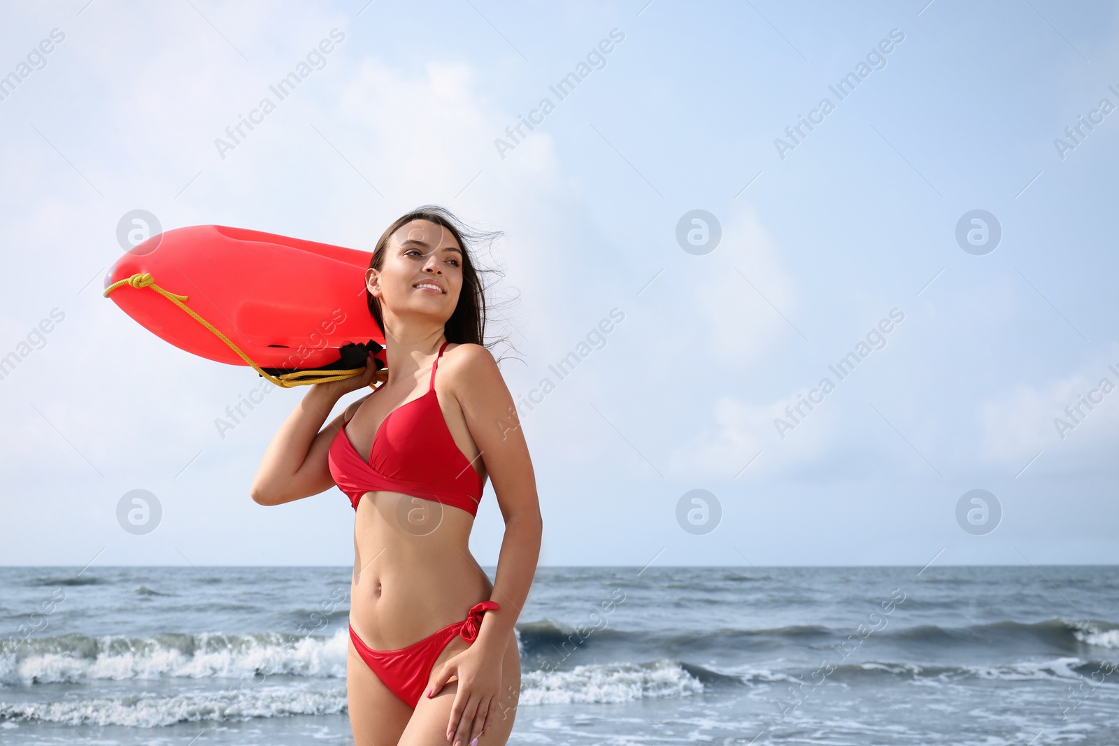 Photo of Beautiful young lifeguard with life buoy near sea