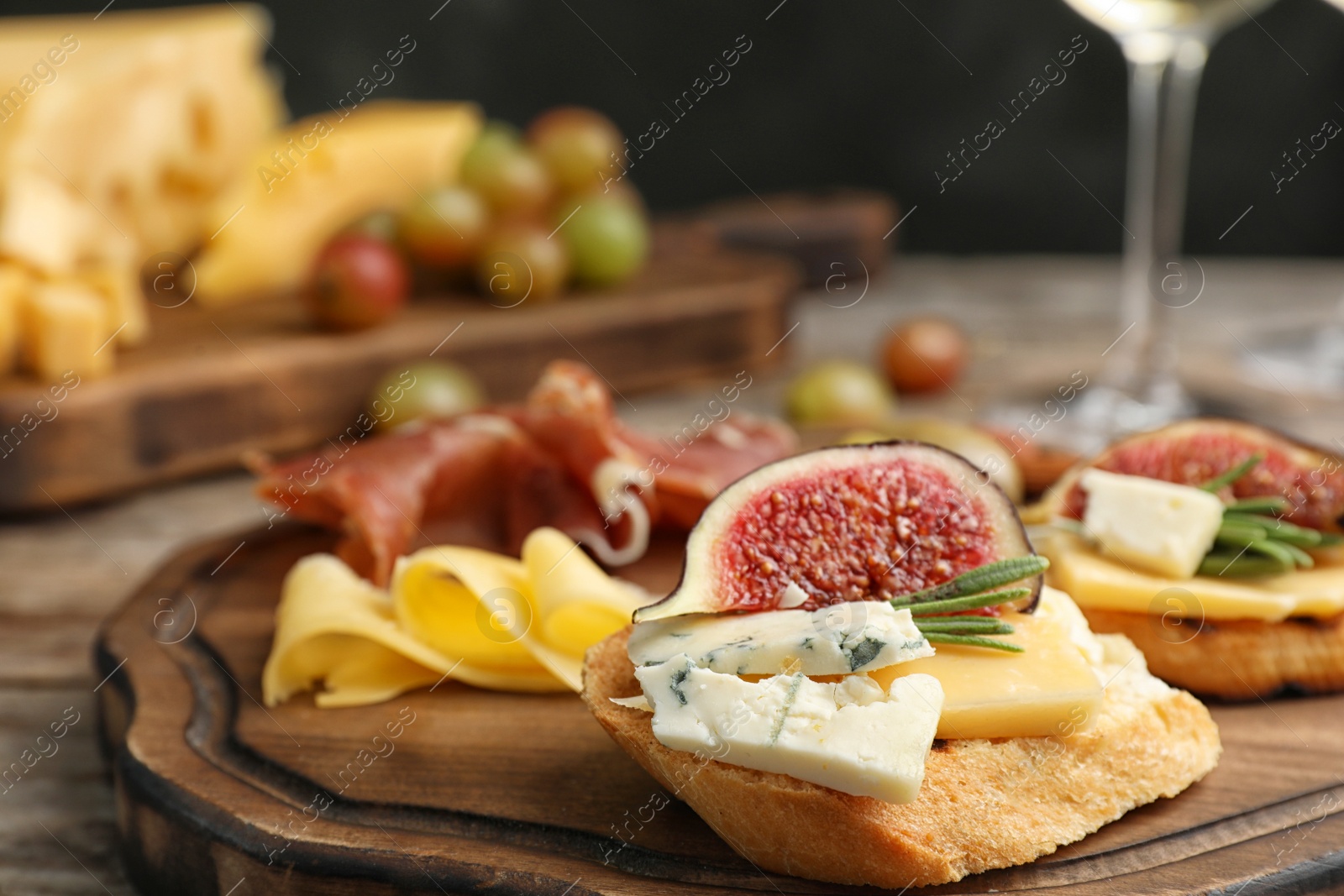 Photo of Sandwich with ripe figs and delicious products on wooden board, closeup