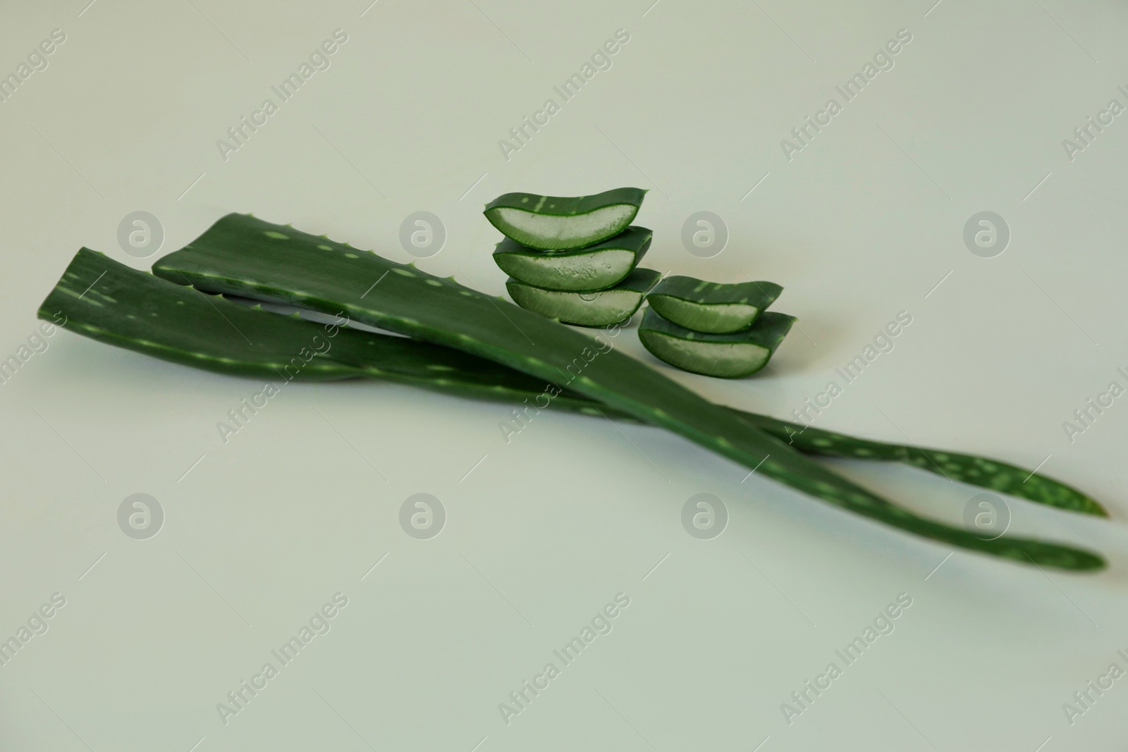 Photo of Green aloe vera leaves and slices on light background