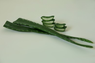 Photo of Green aloe vera leaves and slices on light background