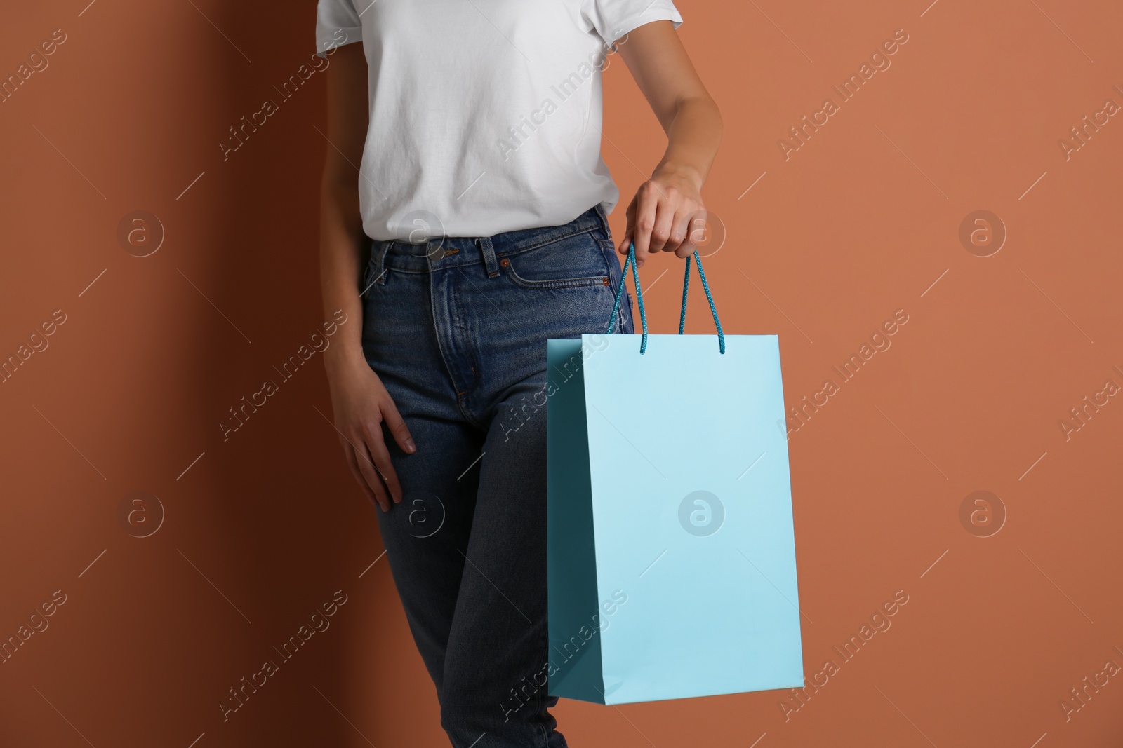 Photo of Woman with paper shopping bag on light brown background, closeup