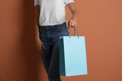 Photo of Woman with paper shopping bag on light brown background, closeup