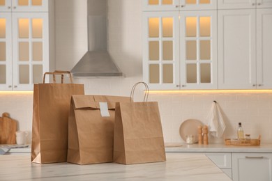 Photo of Paper bags on white marble table in kitchen. Space for text