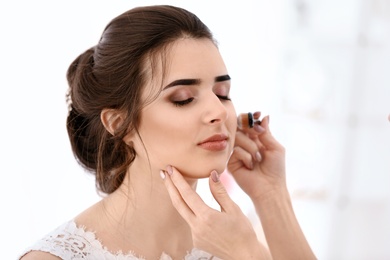 Photo of Professional makeup artist working with young woman in salon