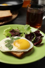 Photo of Plate with tasty fried egg, slice of bread and salad on table, closeup