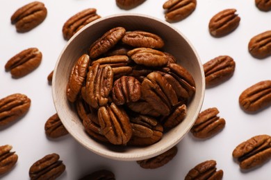 Delicious fresh pecan nuts and bowl on white background, flat lay