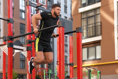 Man training on parallel bars at outdoor gym, low angle view