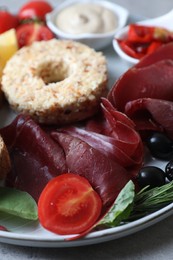 Photo of Delicious bresaola and other ingredients for sandwich on table, closeup