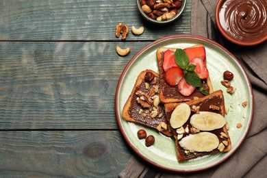 Photo of Tasty toasts with chocolate spread, nuts, strawberries, banana and mint served on wooden table, flat lay. Space for text
