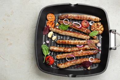 Photo of Grill pan with tasty sausages and vegetables on light table, top view