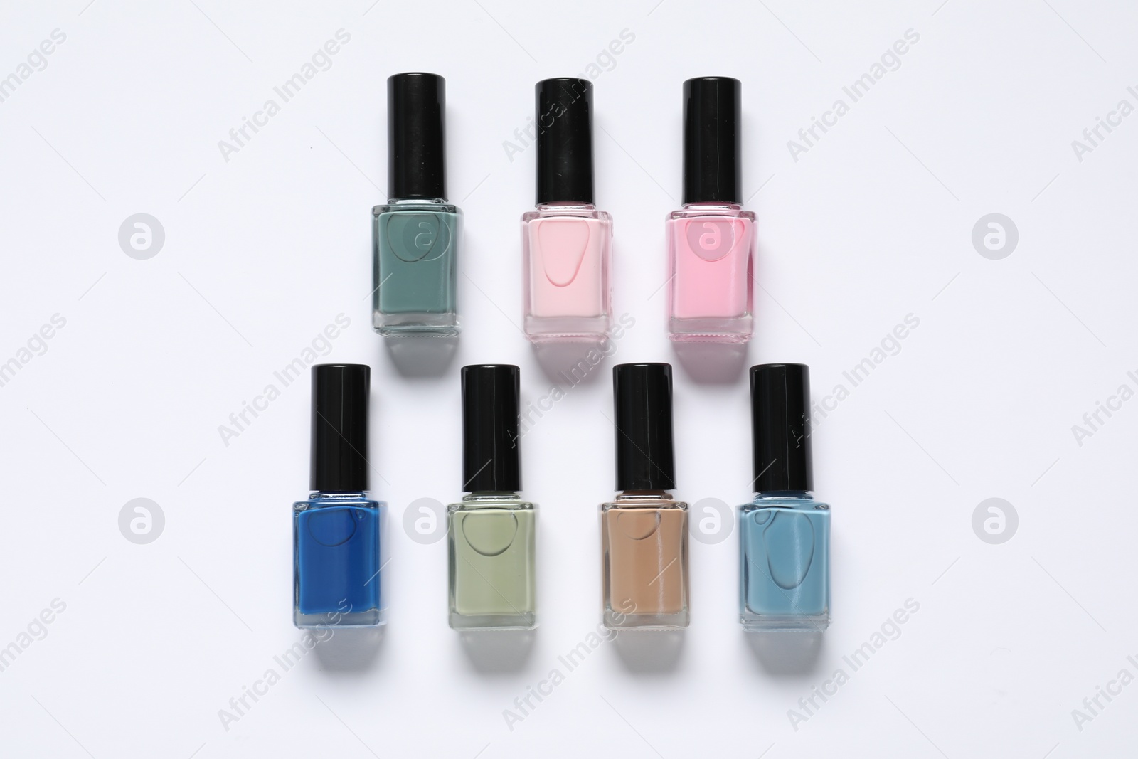 Photo of Nail polishes on white background, flat lay