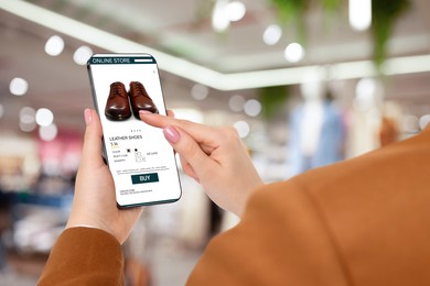 Image of Woman visiting shop to take ordered shoes indoors, closeup. Online store website on device screen