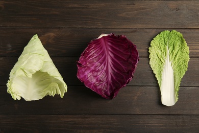 Fresh leaves of different cabbages on wooden table, top view. Healthy food