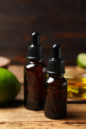 Photo of Lime essential oil in bottles on wooden table