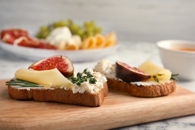 Photo of Sandwiches with ripe figs and cheese on wooden board, closeup