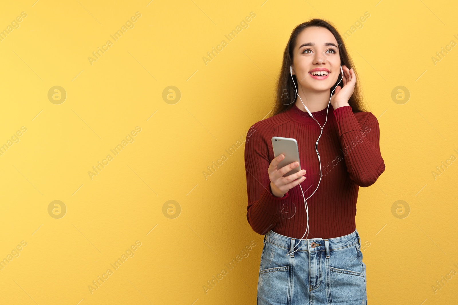 Photo of Young woman using phone for listening to music on color background