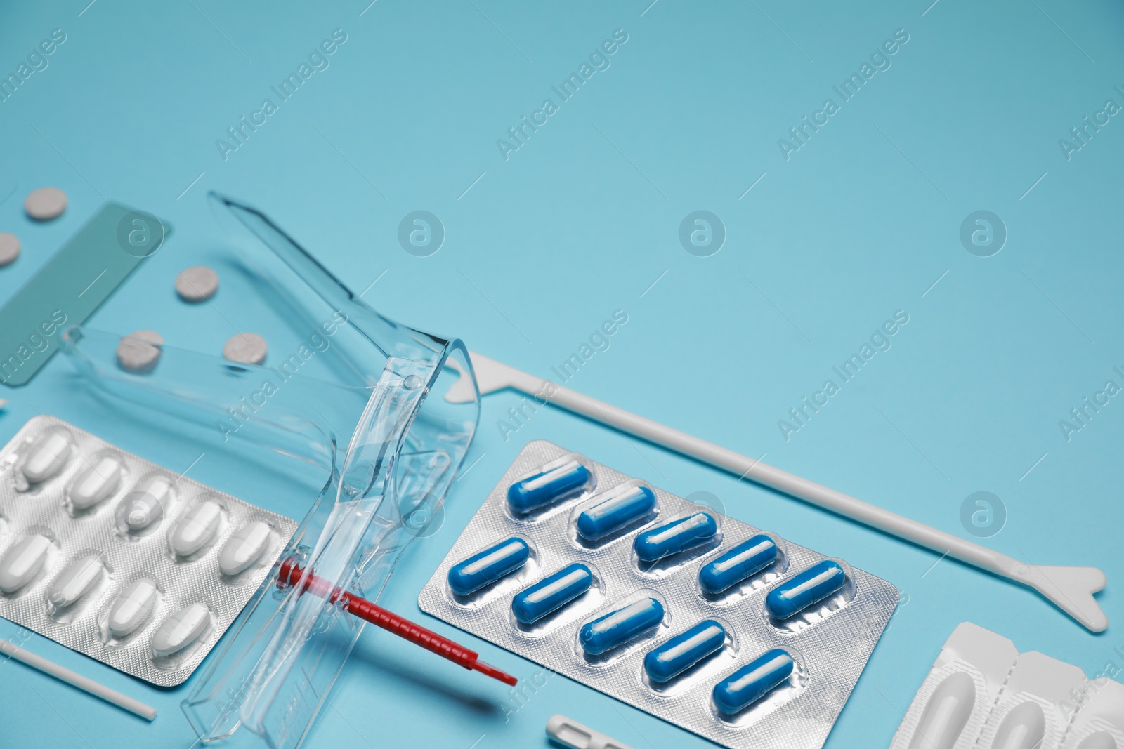 Photo of Sterile gynecological examination kit and pills on light blue background, above view. Space for text