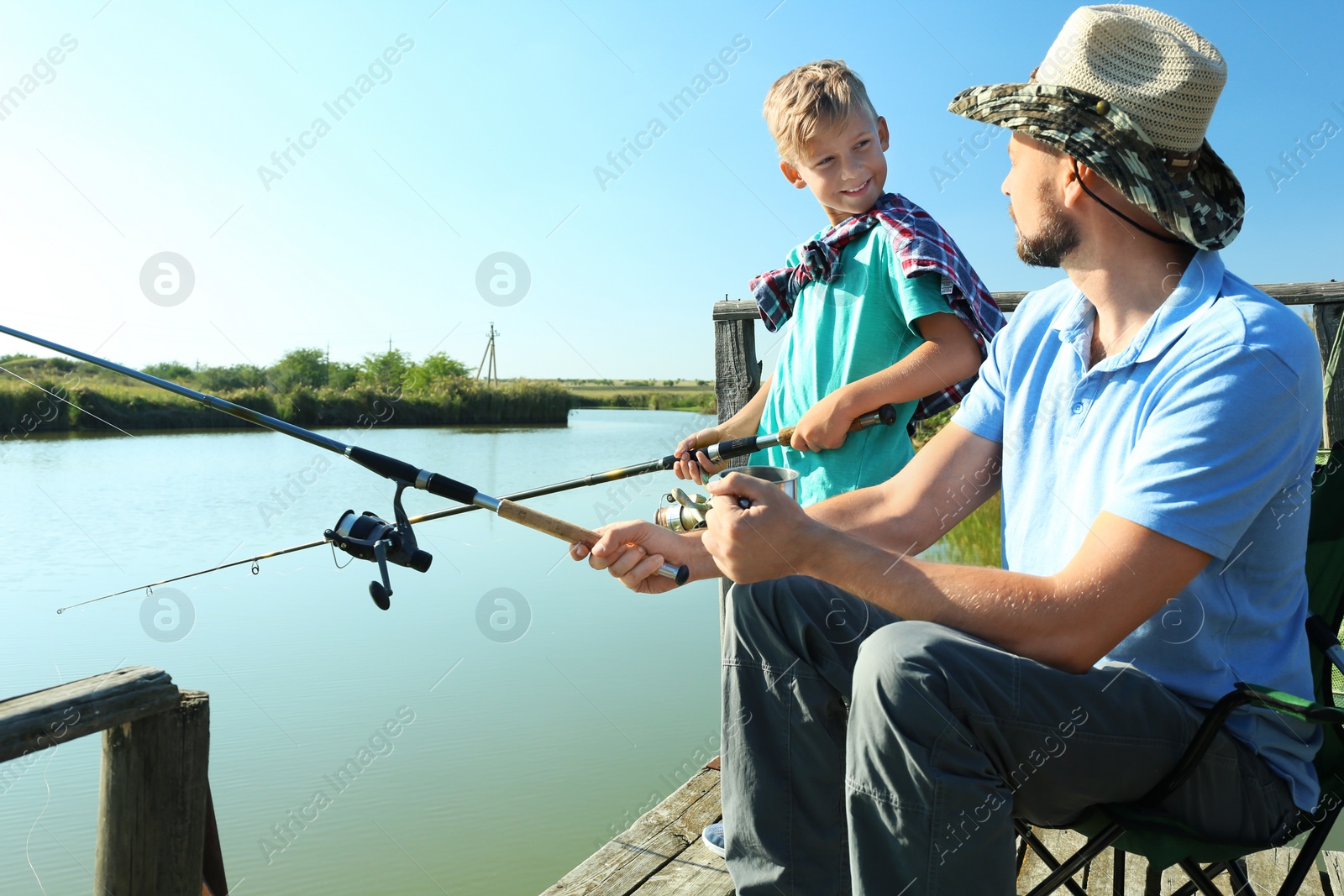 Photo of Father and son fishing together on sunny day