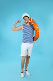 Photo of Sailor with ring buoy showing biceps on light blue background