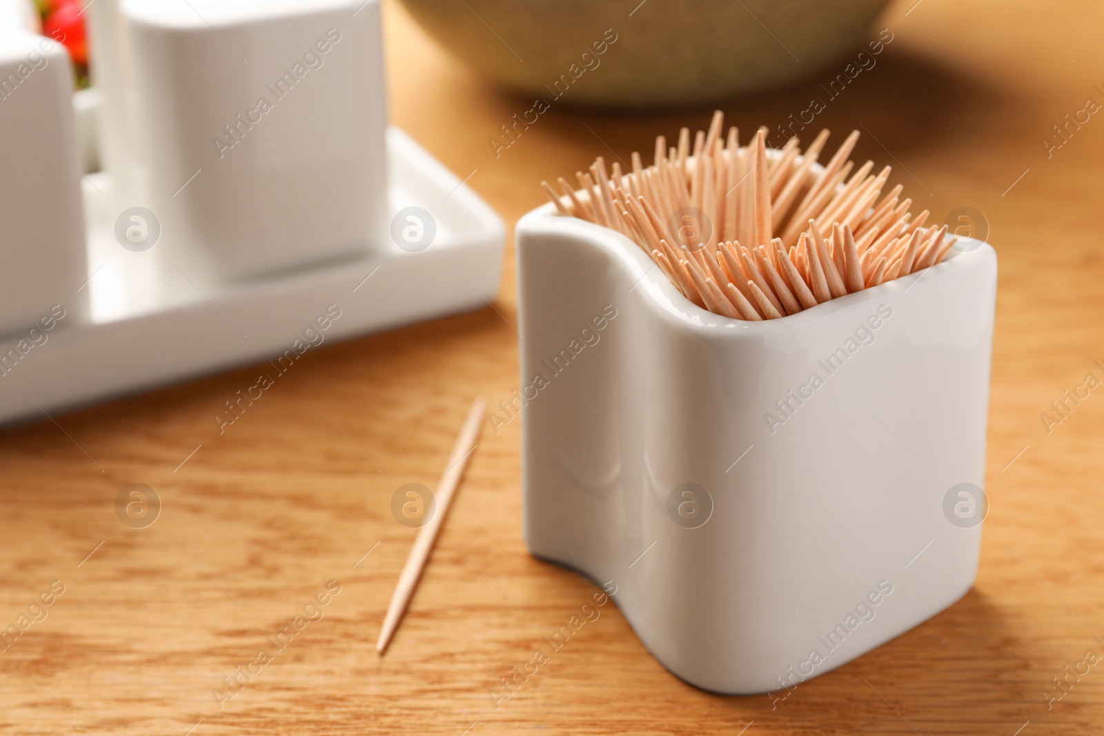 Photo of Holder with many toothpicks on wooden table, closeup. Space for text