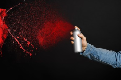 Image of Man spraying red paint on black background, closeup