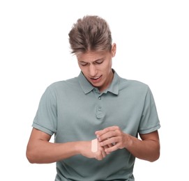 Handsome man putting sticking plaster onto hand on white background