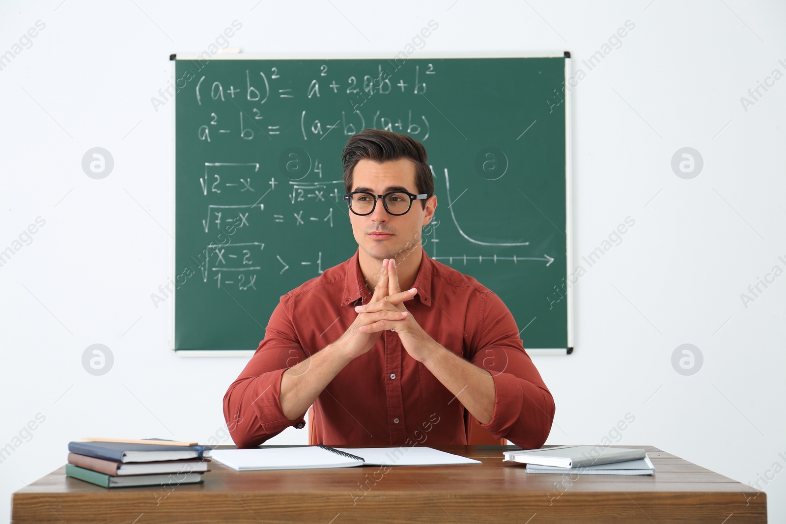 Photo of Young teacher working at table in classroom