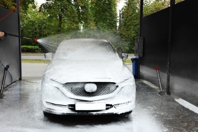 Photo of Man washing auto with high pressure water jet at car wash, closeup