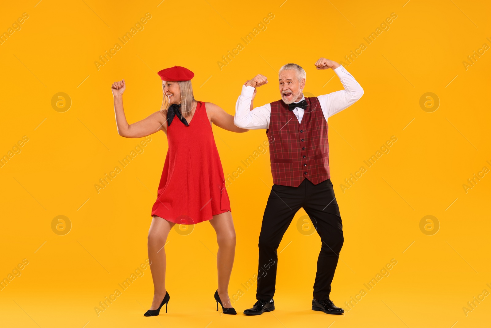 Photo of Senior couple dancing together on orange background