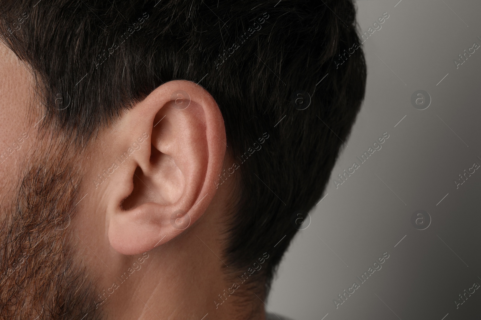 Photo of Man on grey background, closeup of ear