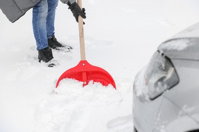 Man removing snow with shovel near car outdoors, closeup