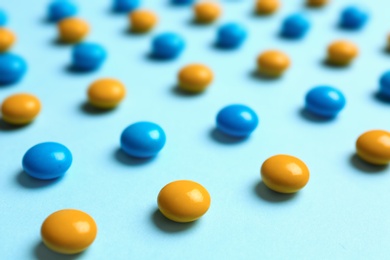 Photo of Delicious bright candies on light blue background, closeup