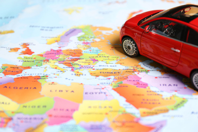 Photo of Red toy car on world map, closeup. Trip planning