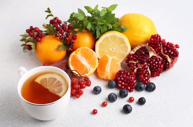 Photo of Cup of delicious immunity boosting tea with ingredients on light grey table