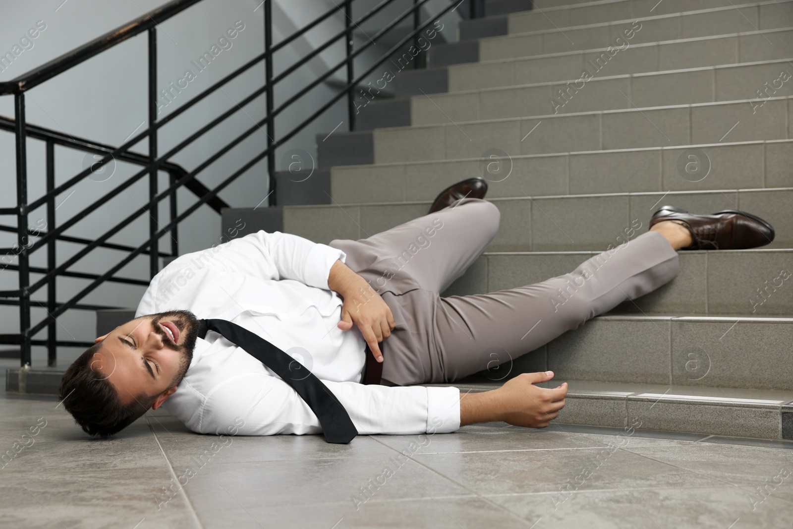 Photo of Man fallen down stairs suffering from pain indoors, space for text