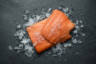 Fresh raw salmon with ice on black table, flat lay
