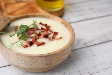 Photo of Delicious potato soup with bacon and microgreens in bowl on wooden table, closeup. Space for text