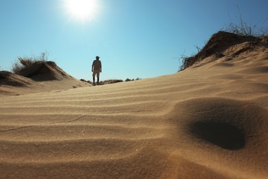 Photo of Man in desert on sunny day, back view