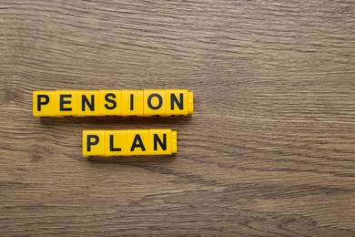 Words Pension Plan made of yellow cubes on wooden table, flat lay. Space for text