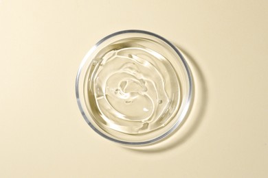 Photo of Petri dish with liquid on beige background, top view
