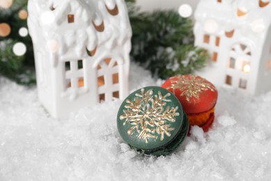 Different decorated Christmas macarons on table with artificial snow, space for text