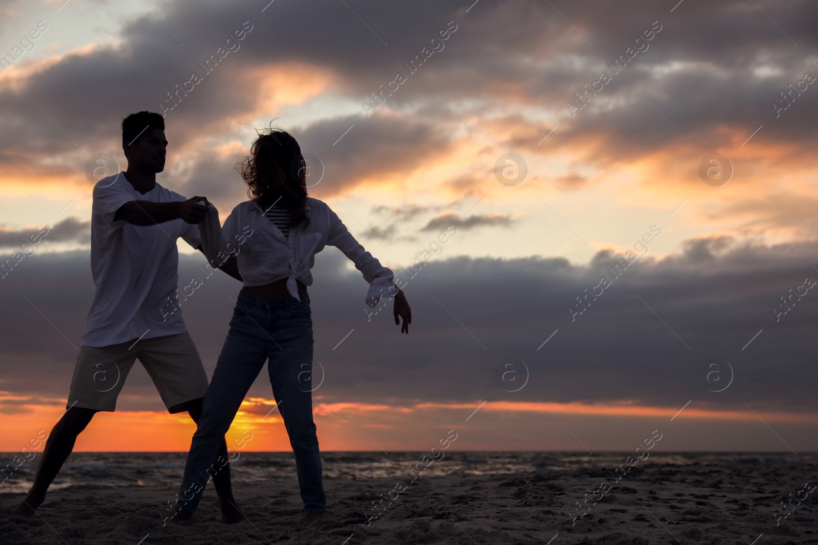 Photo of Happy couple dancing on beach at sunset