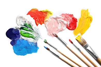 Photo of Paint strokes and different brushes on white background, top view