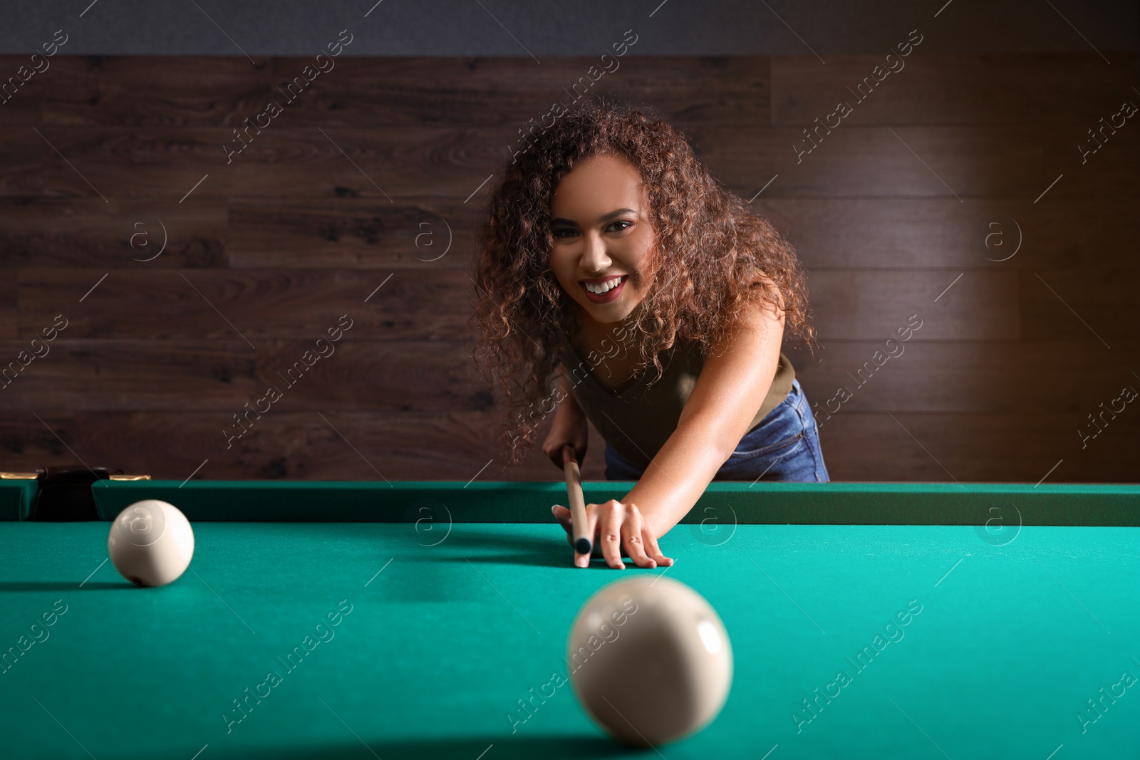 Photo of Young African-American woman playing Russian billiard indoors