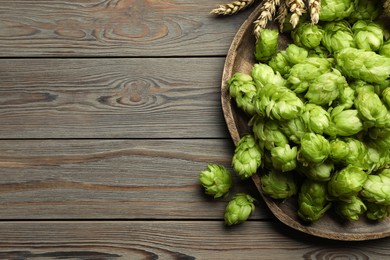 Tray with fresh green hops and wheat ears on wooden table, flat lay. Space for text