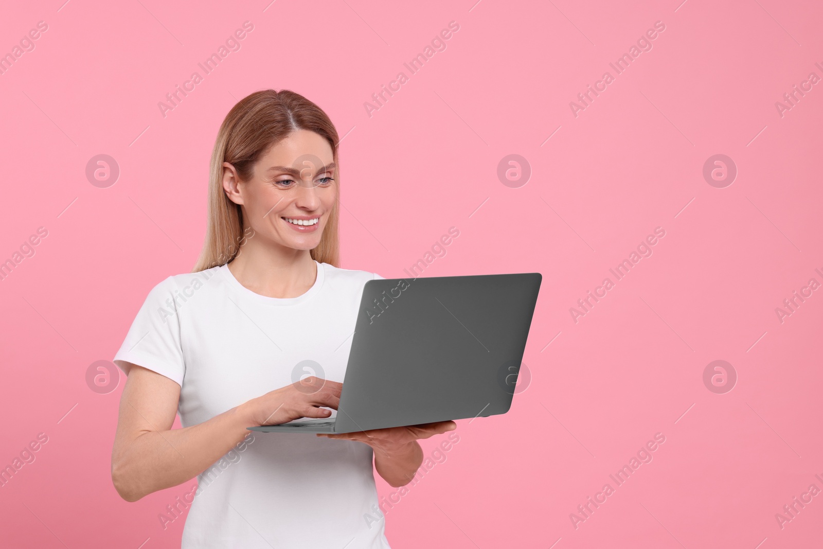 Photo of Happy woman with laptop on pink background. Space for text