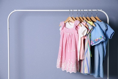 Rack with stylish child clothes on color background