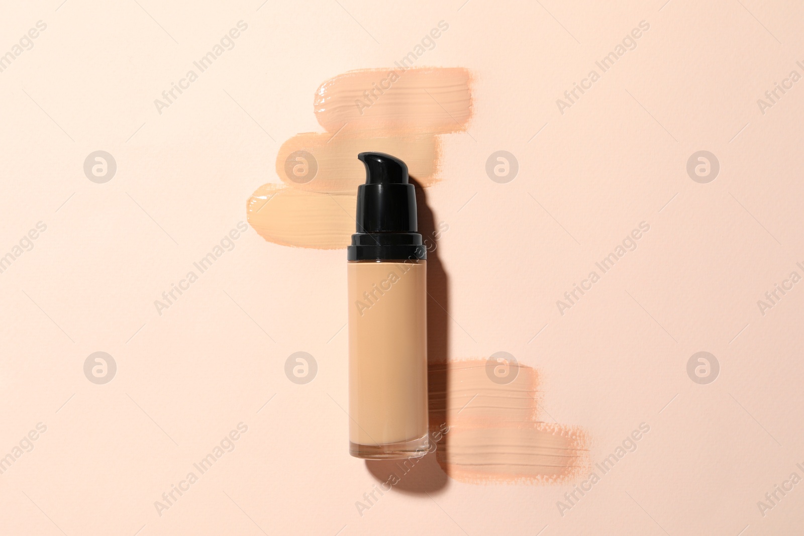 Photo of Liquid foundation and swatches on beige background, top view