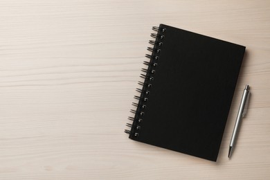 Notebook and pen on white wooden table, flat lay . Space for text